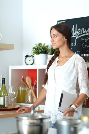 Young woman standing near desk in the kitchenの写真素材