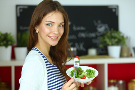 Young woman eating salad and holding a mixed saladの写真素材