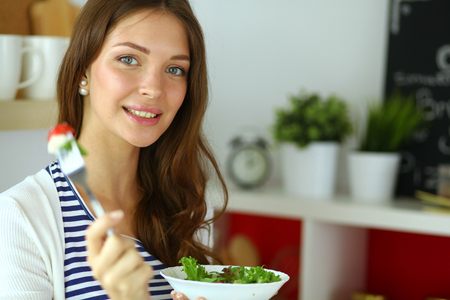 Young woman eating salad and holding a mixed saladの写真素材