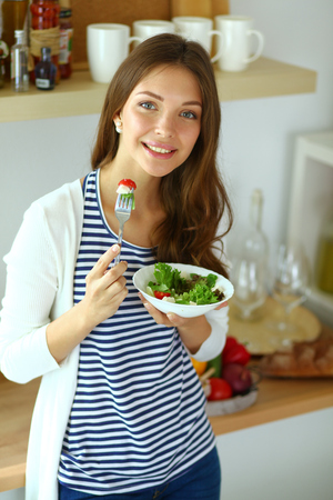 Young woman eating salad and holding a mixed saladの写真素材