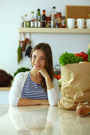 Young woman sitting near desk in the kitchenの写真素材