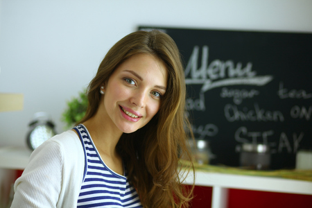 Young woman standing near desk in the kitchen.の写真素材