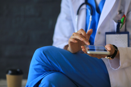 Young woman doctor sitting with your phoneの写真素材