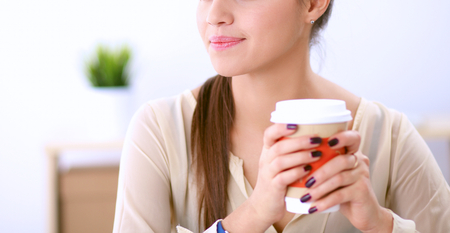 Young businesswoman sitting on the desk with with cupの写真素材