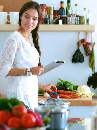 Young woman using a tablet computer to cook in her kitchen .の写真素材