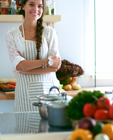 Young woman standing near desk in the kitchenの写真素材