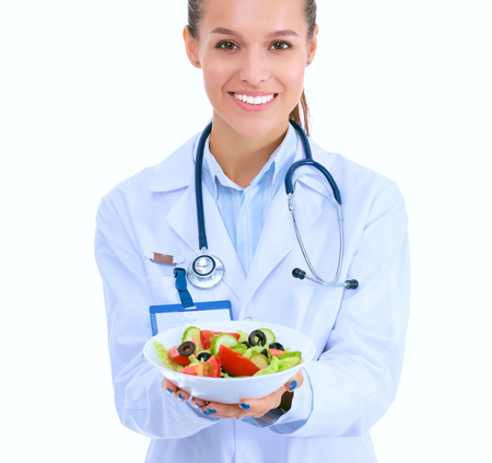 Portrait of a beautiful woman doctor holding a plate with fresh vegetablesの写真素材