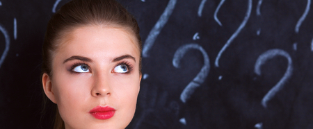 Young girl with question mark on a gray background .の写真素材
