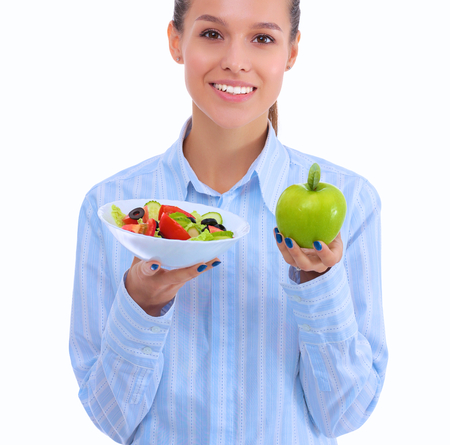Portrait of a beautiful woman doctor holding a plate with fresh vegetables and green appleの写真素材