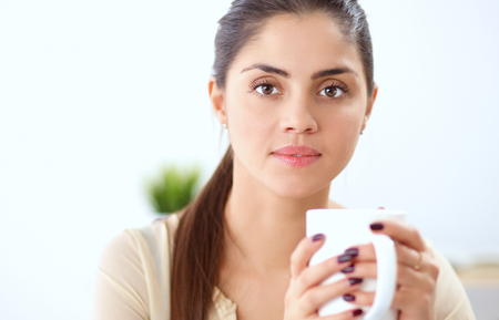 Young businesswoman sitting on the desk with with cupの写真素材