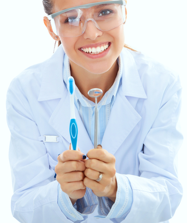 Beautiful female dentist doctor holding and showing a toothbrush isolated on a white backgroundの写真素材