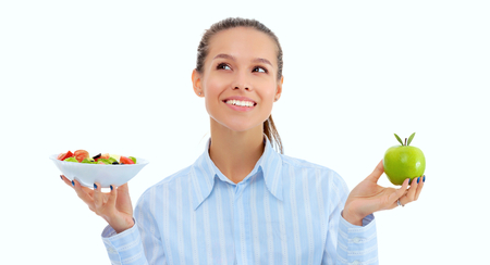 Portrait of a beautiful woman doctor holding a plate with fresh vegetables and green appleの写真素材
