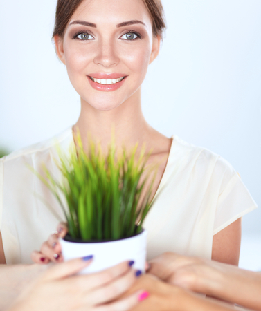 Beautiful woman holding pot with a plant, standing .の写真素材