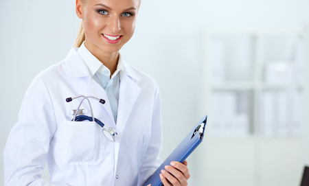 Smiling female doctor with a folder in uniform standingの写真素材