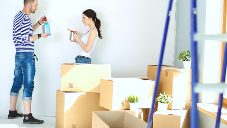 Portrait of happy smiling young couple  painting interior wall of new house.の写真素材