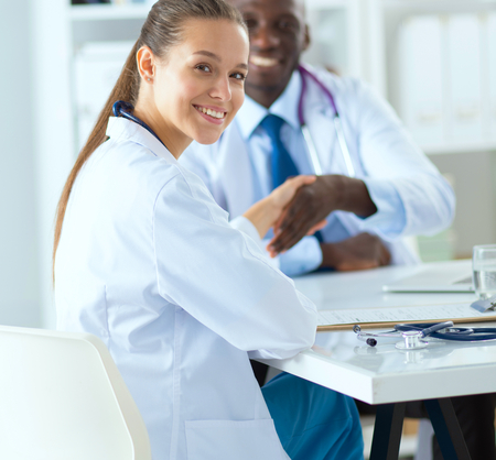 Two happy smiling young medical people handshaking at officeの写真素材