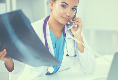 Young female doctor studying x-ray image sitting on the desk.の写真素材