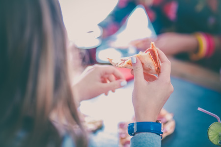 Beautiful young woman eating a slice of pizzaの写真素材