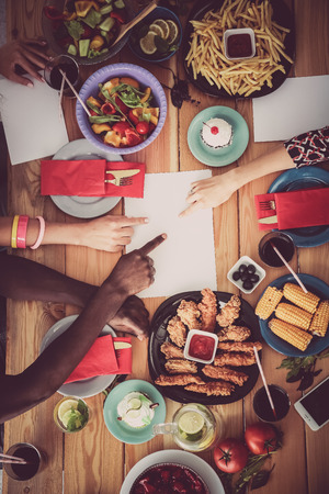 Top view of group of people having dinner together while sitting at wooden tableの写真素材