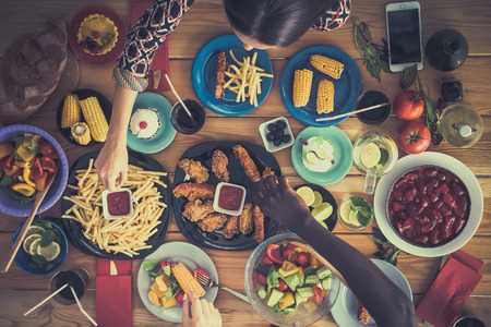 Top view of group of people having dinner together while sitting at wooden tableの写真素材