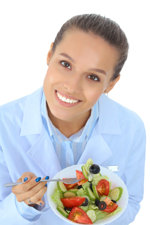 Portrait of a beautiful woman doctor holding a plate with fresh vegetablesの写真素材