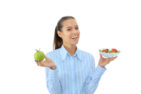 Portrait of a beautiful woman doctor holding a plate with fresh vegetables and green appleの写真素材