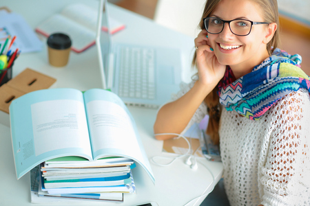 Young woman sitting at a desk among booksの写真素材