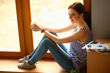 Girl sitting on windowsill at new homeの写真素材