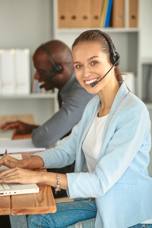 Business people with headsets using computers in officeの写真素材