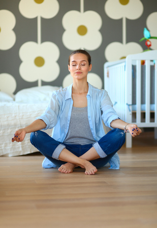 Young woman doing yoga at home in the lotus positionの写真素材