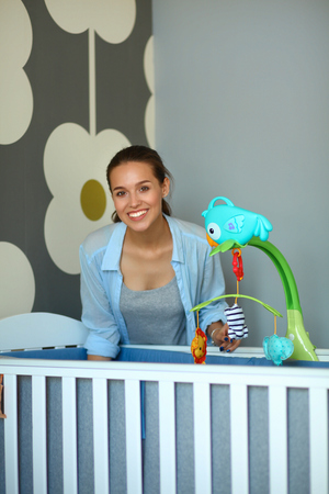 Young woman standing near children's cot.の写真素材