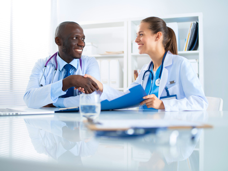 Two happy smiling young medical people handshaking at officeの写真素材