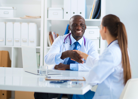 Two happy smiling young medical people handshaking at officeの写真素材