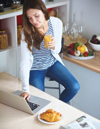 Young woman sitting near desk in the kitchenの写真素材