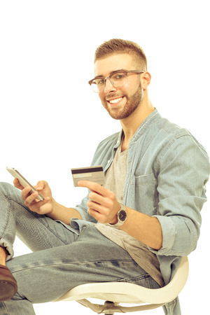 Young man sitting on chair and holding credit cardの写真素材