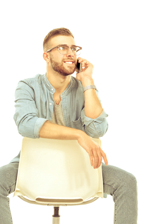 Young man sitting on chair and using mobile phoneの写真素材