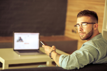 Young man using phone and works on the laptopの写真素材