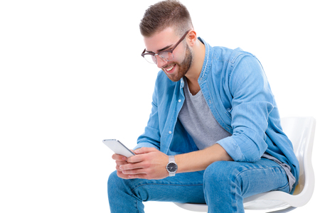 Young man sitting on chair and using mobile phoneの写真素材