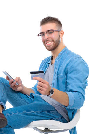 Young man sitting on chair and holding credit cardの写真素材