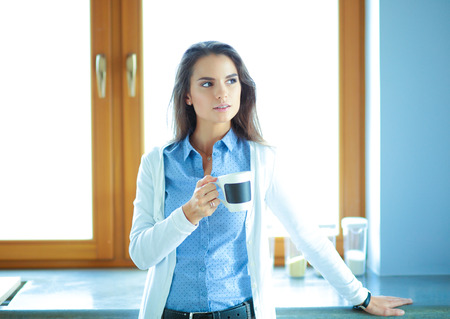 happy woman drinking tea in the kitchen at homeの写真素材