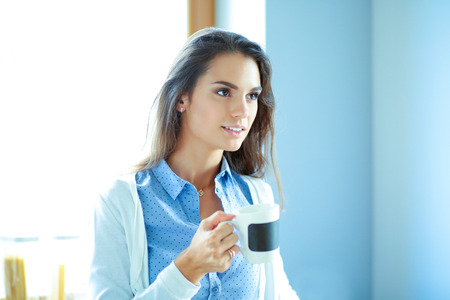 happy woman drinking tea in the kitchen at homeの写真素材