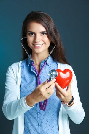 A doctor with stethoscope examining red heartの写真素材