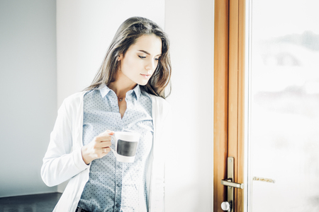 happy woman drinking tea in the kitchen at homeの写真素材