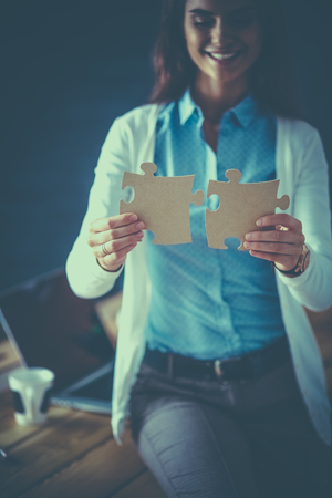 Business woman holding and pointing to a puzzle pieceの写真素材
