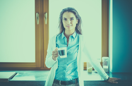 happy woman drinking tea in the kitchen at homeの写真素材