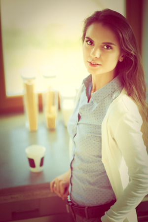 Young woman is standing near windowの写真素材