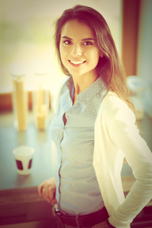 Young woman is standing near windowの写真素材