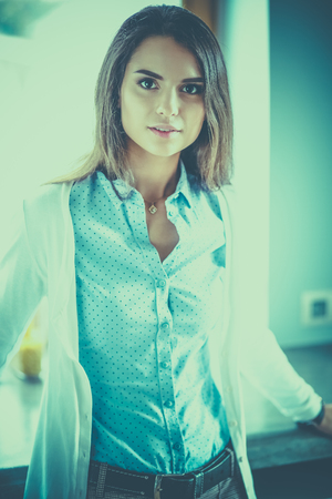 Young woman is standing near windowの写真素材