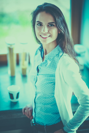Young woman is standing near windowの写真素材