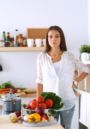 Young woman standing by the stove in the kitchen .の写真素材